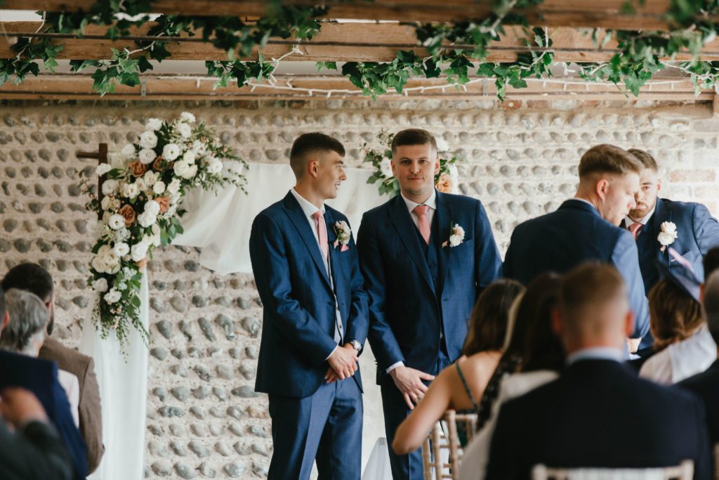A Groom and his Best Man standing at the altar at Montague Farm in front of a romantic flower archway as he waits for the ceremony to begin