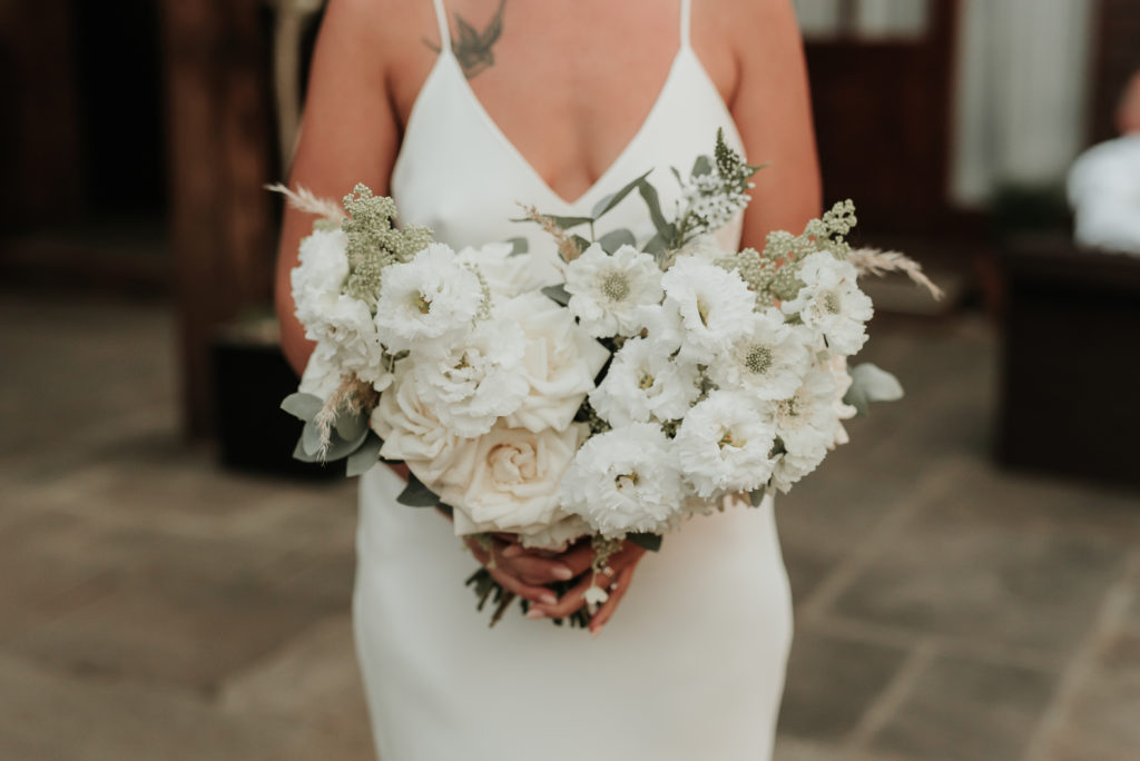 A bride holding her beautiful white bridal bouquet at West Sussex wedding venue Long Furlong Barn