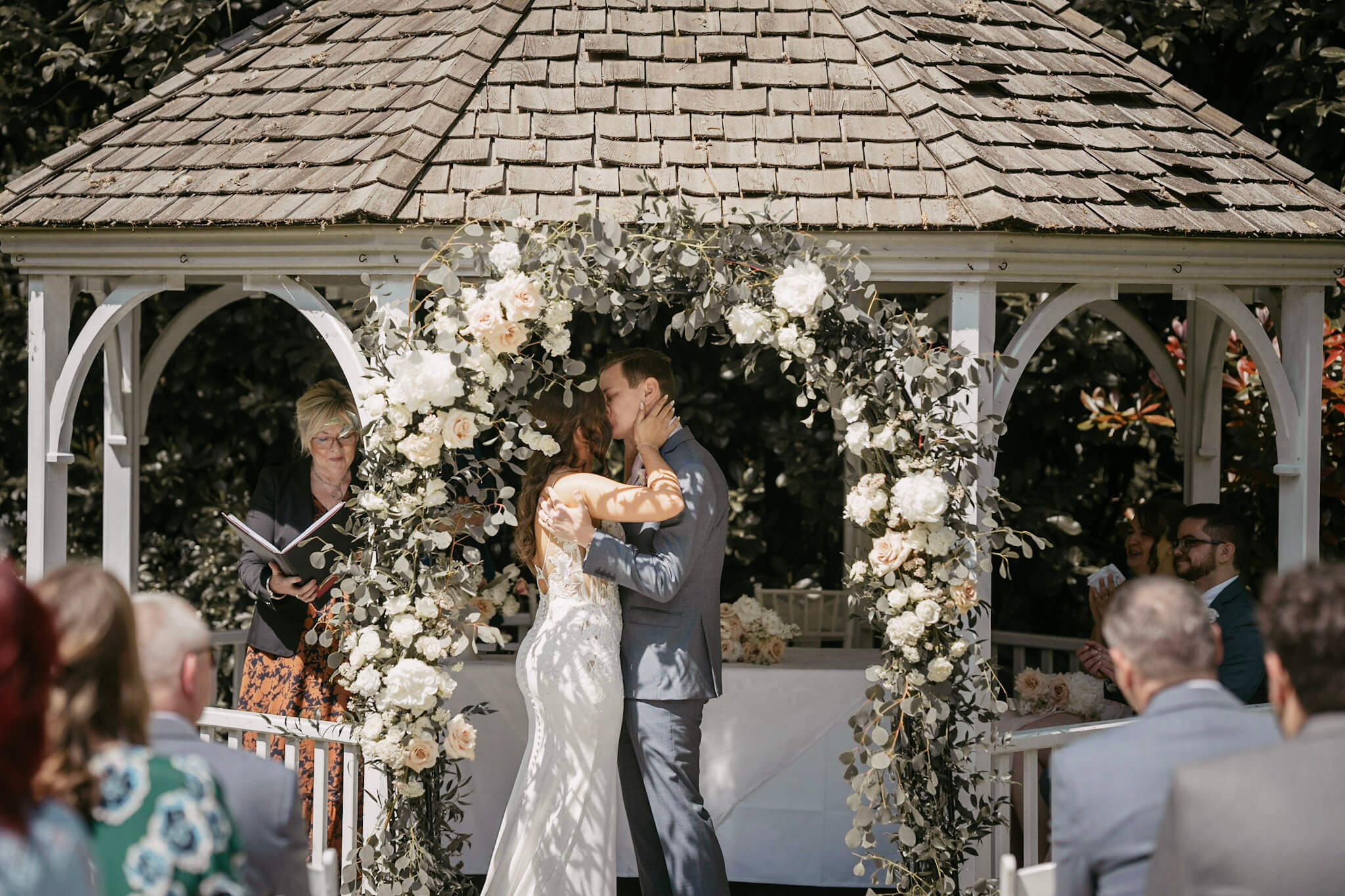 Couple kissing under wedding flower archway at a wedding